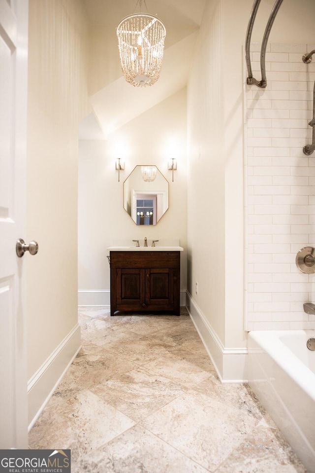full bath with baseboards, washtub / shower combination, vanity, and an inviting chandelier