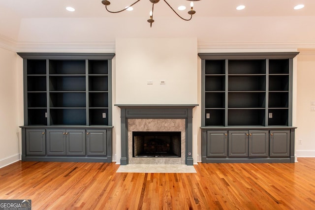 unfurnished living room with baseboards, a fireplace, recessed lighting, a notable chandelier, and light wood-type flooring