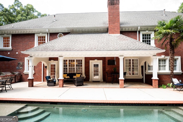 rear view of property featuring a patio area, a chimney, roof with shingles, and an outdoor hangout area