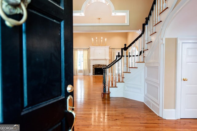 entryway featuring stairway, arched walkways, wood finished floors, and a fireplace