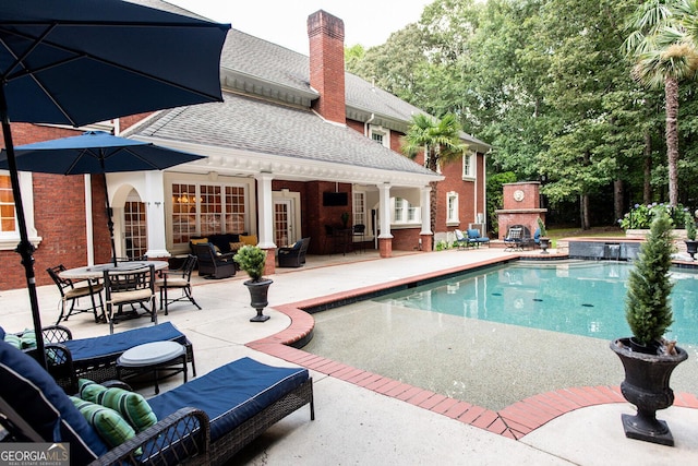 view of swimming pool with a patio and an outdoor living space with a fireplace