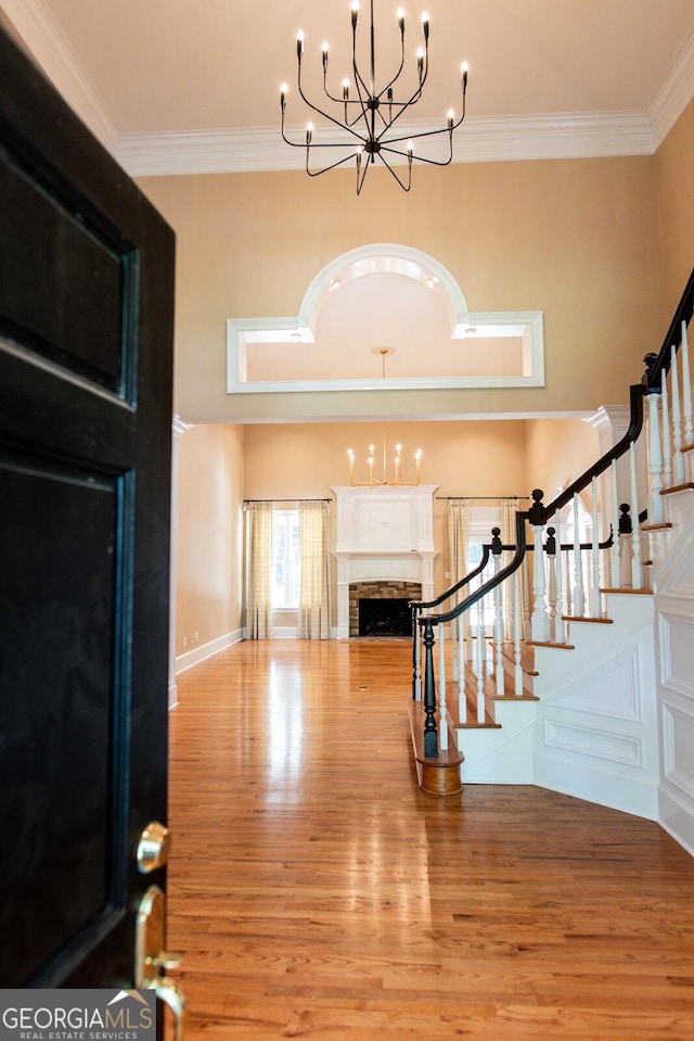 foyer with stairway, an inviting chandelier, a fireplace, and crown molding