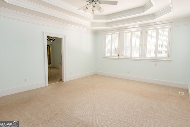 spare room with a raised ceiling, ornamental molding, carpet, and a healthy amount of sunlight