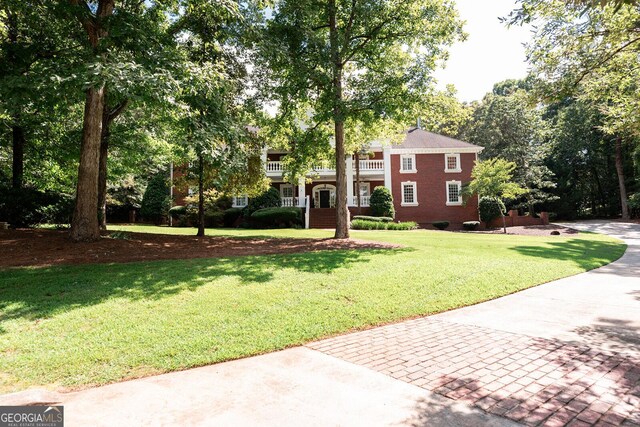 greek revival inspired property featuring a front yard and a balcony