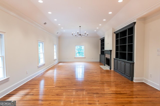 unfurnished living room with light wood-type flooring, a notable chandelier, ornamental molding, recessed lighting, and baseboards