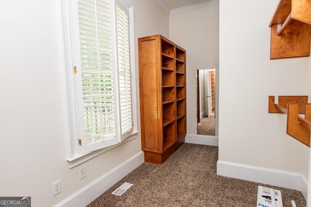 hall featuring visible vents, baseboards, crown molding, and carpet