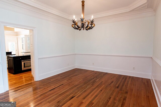 unfurnished dining area featuring baseboards, wood-type flooring, a chandelier, and ornamental molding
