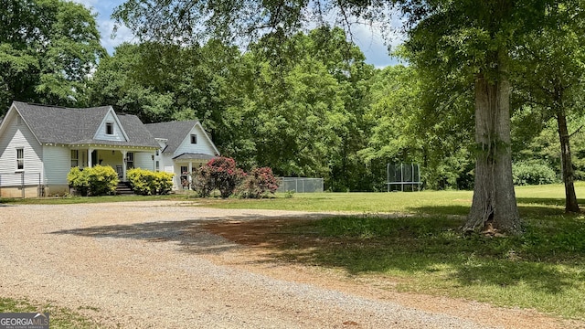 view of front of property featuring driveway, a trampoline, fence, a front lawn, and a shingled roof
