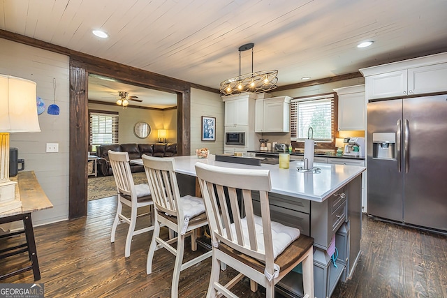 kitchen with dark wood-style floors, stainless steel fridge with ice dispenser, a breakfast bar area, white cabinetry, and pendant lighting
