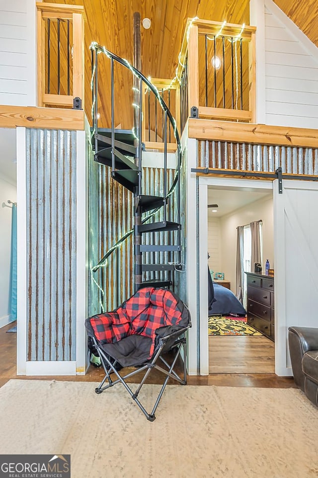 interior details with a barn door, wood finished floors, and wooden walls