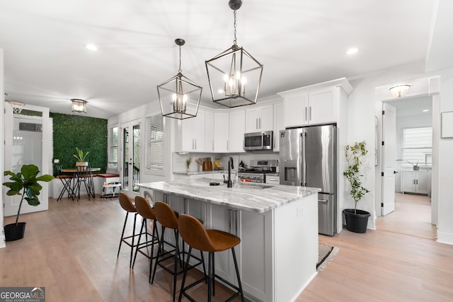 1290 Westboro Dr SW, Atlanta, GA 30310 - kitchen with light wood-type flooring, a kitchen breakfast bar, appliances with stainless steel finishes, white cabinets, and light stone countertops