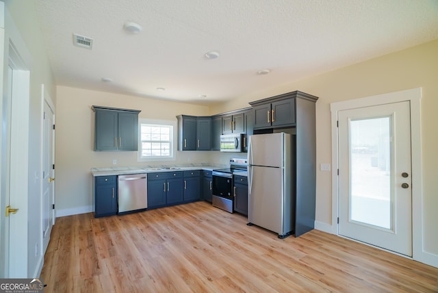 42 Walton Way, Hazlehurst, GA 31539 - kitchen featuring appliances with stainless steel finishes, light countertops, light wood-style flooring, and blue cabinets