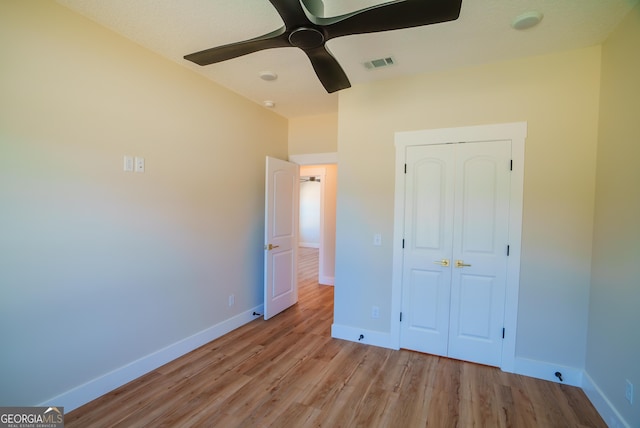 unfurnished bedroom with wood finished floors, visible vents, a closet, baseboards, and ceiling fan
