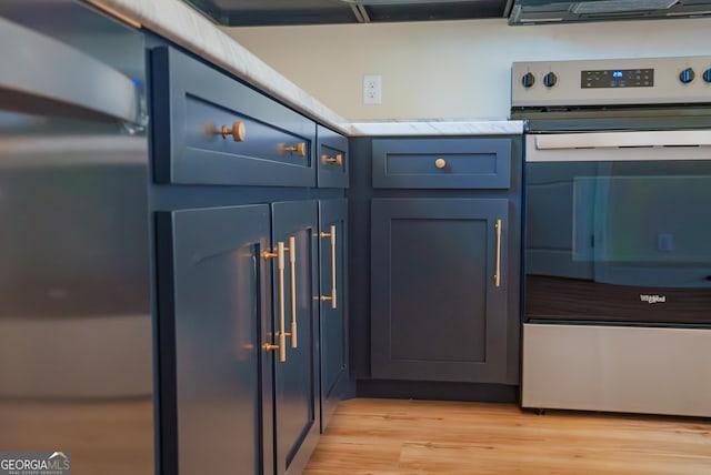 42 Walton Way, Hazlehurst, GA 31539 - kitchen with stainless steel electric range, light countertops, light wood-type flooring, blue cabinetry, and fridge
