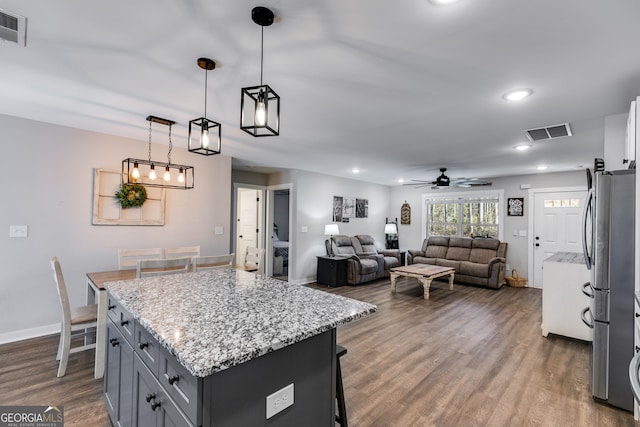 132 Pinnacle Way, Carrollton, GA 30117 - kitchen featuring a breakfast bar area, light stone counters, visible vents, dark wood-style flooring, and freestanding refrigerator