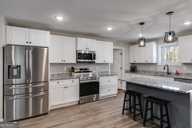 132 Pinnacle Way, Carrollton, GA 30117 - kitchen with light wood-type flooring, a breakfast bar, a sink, stainless steel appliances, and white cabinets