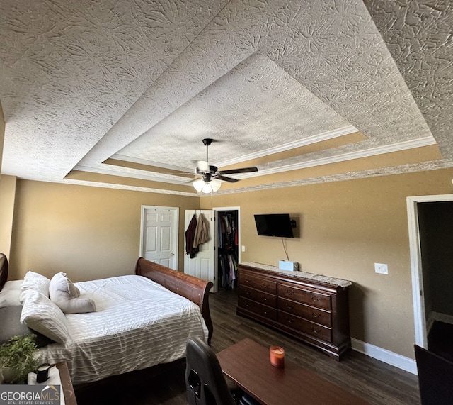 bedroom featuring dark wood finished floors, a raised ceiling, a textured ceiling, and ornamental molding
