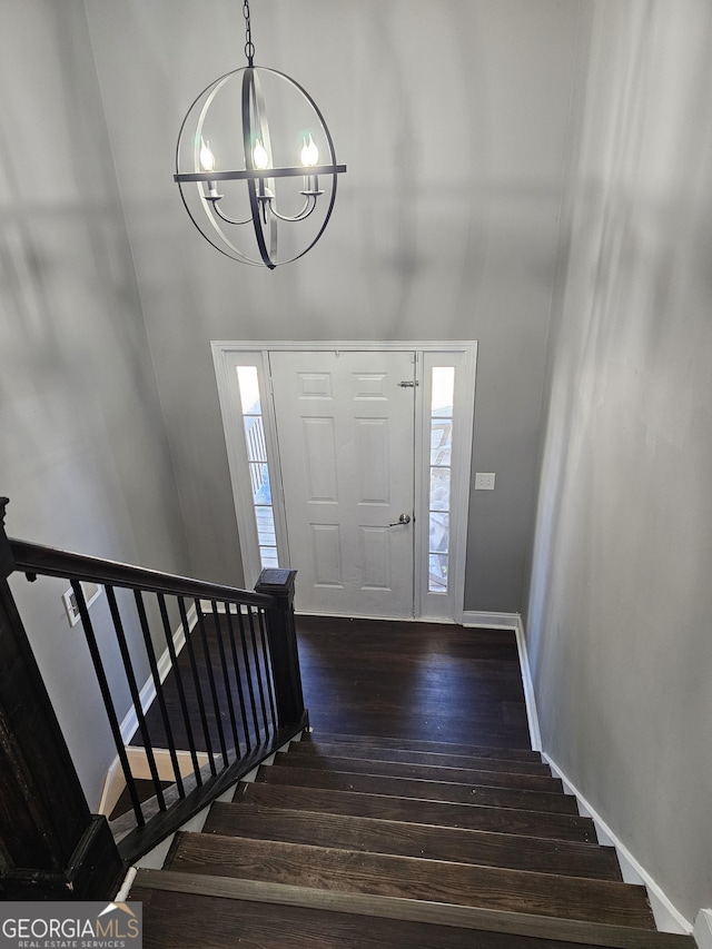 foyer featuring stairway, plenty of natural light, an inviting chandelier, and dark wood-style floors
