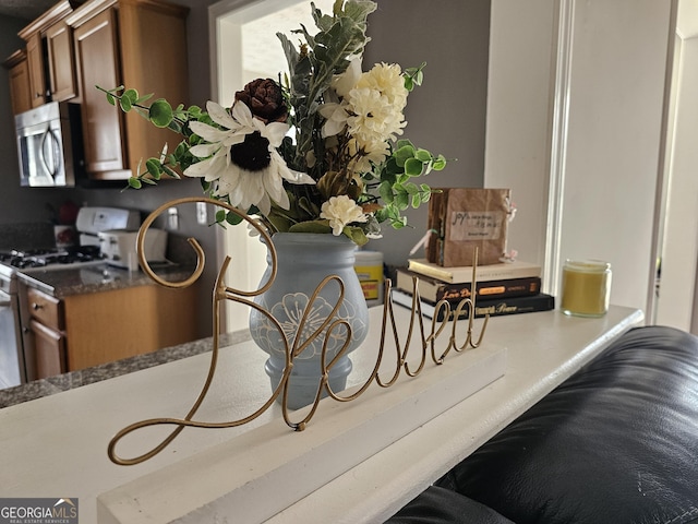 room details featuring stainless steel microwave, brown cabinets, and white gas range