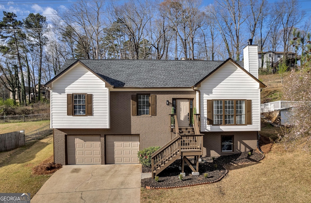 2121 Lindley Ln NW, Kennesaw, GA 30144 - view of front of home featuring driveway, a chimney, fence, brick siding, and a garage