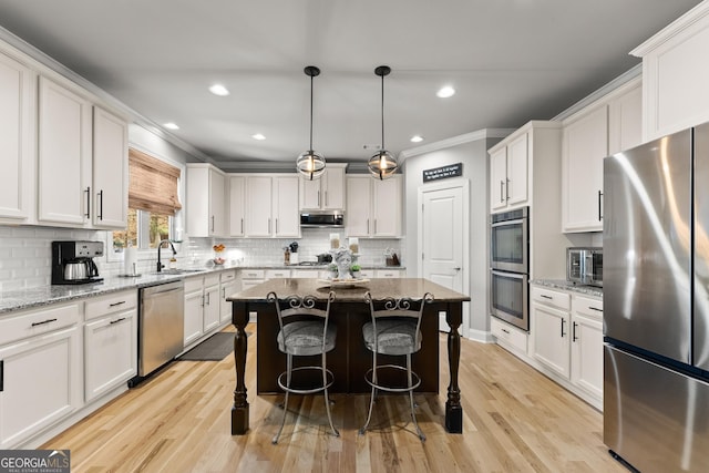 1351 Ashbury Park Dr, Hoschton, GA 30548 - kitchen featuring appliances with stainless steel finishes, white cabinets, a kitchen island, recessed lighting, and ornamental molding