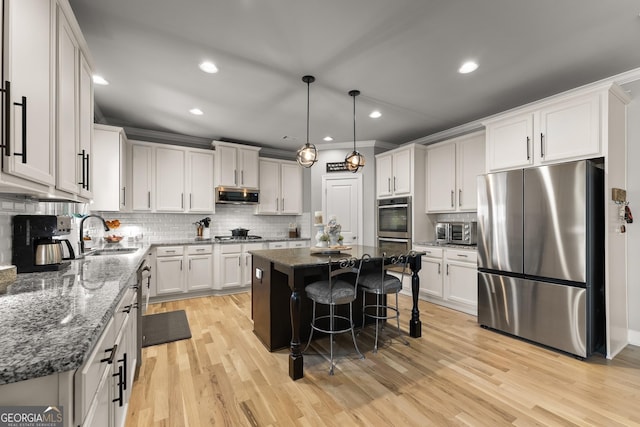 1351 Ashbury Park Dr, Hoschton, GA 30548 - kitchen featuring appliances with stainless steel finishes, a center island, backsplash, light wood-type flooring, and dark stone countertops