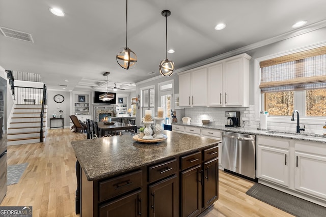 1351 Ashbury Park Dr, Hoschton, GA 30548 - kitchen with stainless steel dishwasher, crown molding, plenty of natural light, white cabinets, and a stone fireplace