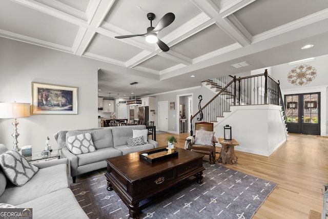 living room featuring crown molding, stairs, wood finished floors, a ceiling fan, and coffered ceiling