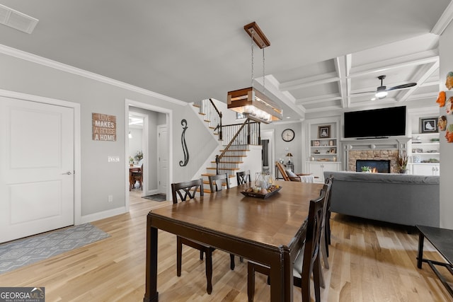 1351 Ashbury Park Dr, Hoschton, GA 30548 - dining area featuring crown molding, a ceiling fan, a fireplace, stairs, and light wood-style floors