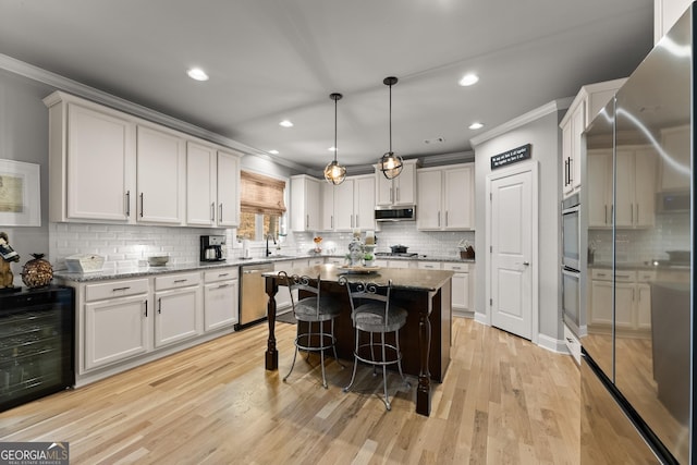 kitchen featuring crown molding, appliances with stainless steel finishes, a center island, wine cooler, and backsplash