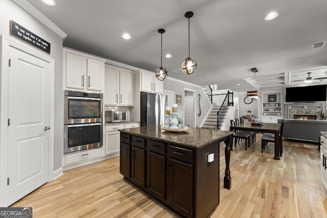kitchen with stainless steel appliances, visible vents, ornamental molding, and light wood-style floors