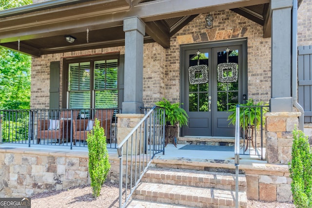 1351 Ashbury Park Dr, Hoschton, GA 30548 - entrance to property featuring french doors, brick siding, and covered porch