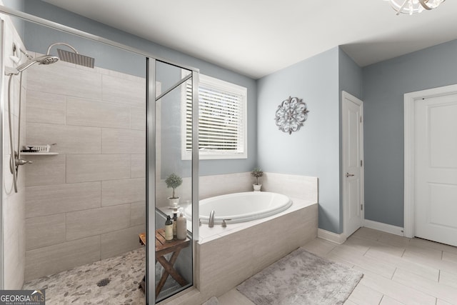 full bath featuring baseboards, a garden tub, and a stall shower