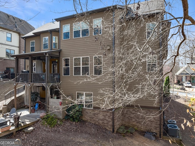 back of house featuring a patio, brick siding, and stairs