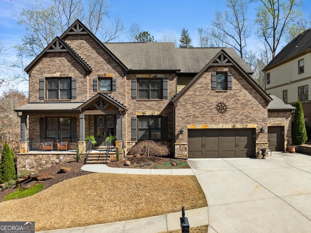 craftsman inspired home with a porch, roof with shingles, brick siding, and concrete driveway