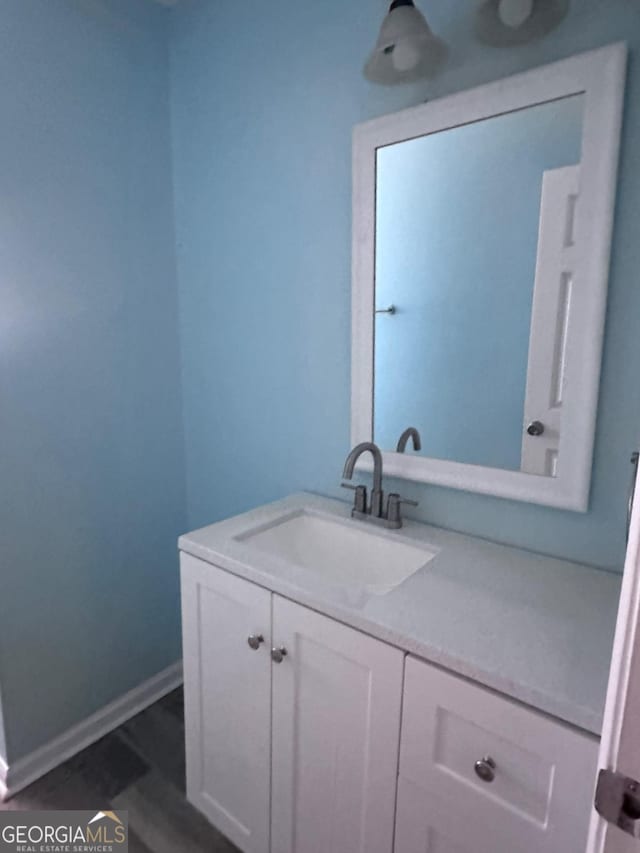 bathroom with vanity, wood finished floors, and baseboards