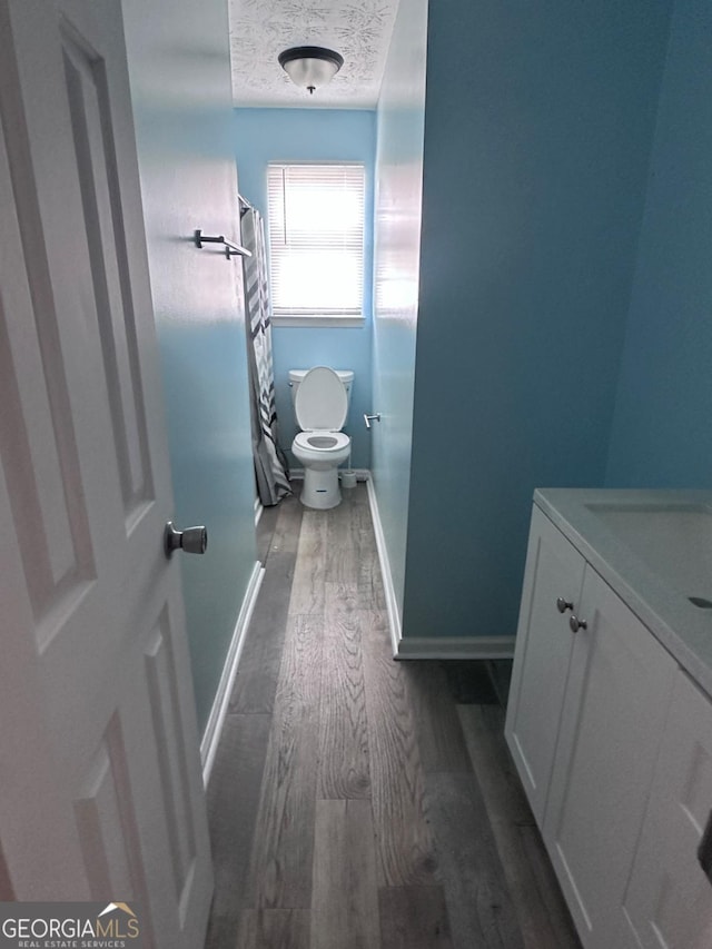 full bath with vanity, wood finished floors, baseboards, a textured ceiling, and toilet