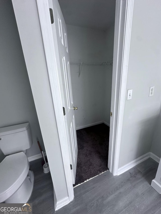 bathroom featuring toilet, wood finished floors, and baseboards