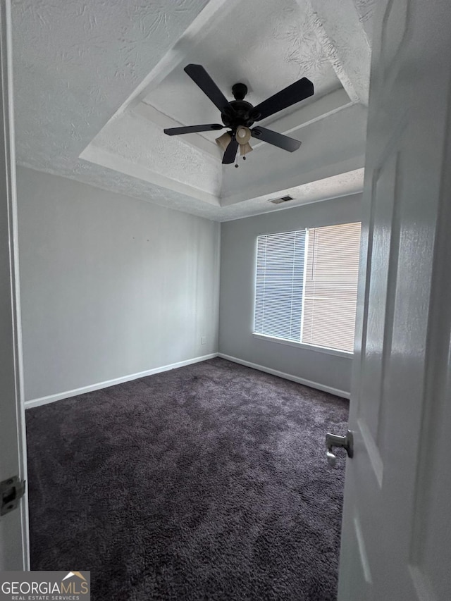 unfurnished room with visible vents, a ceiling fan, a textured ceiling, carpet, and a raised ceiling