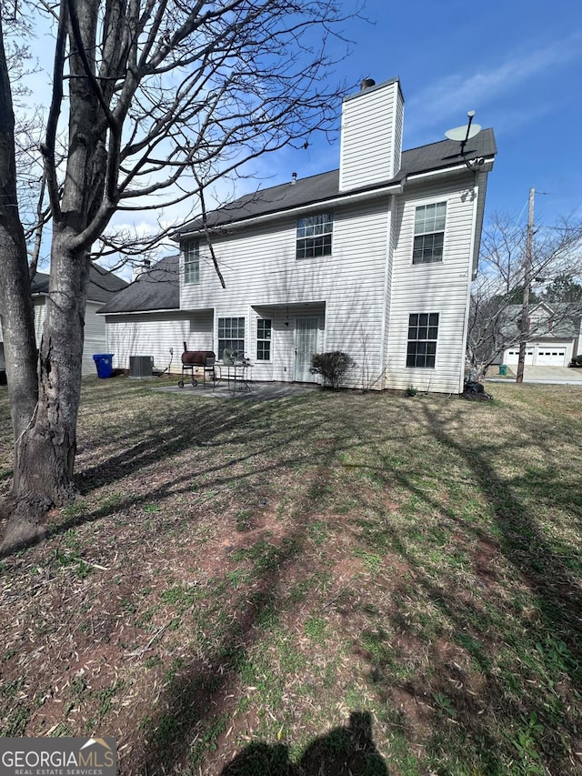 back of property featuring a patio, a lawn, central AC, and a chimney