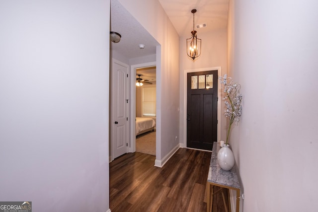 foyer entrance with an inviting chandelier, baseboards, dark wood-style flooring, and visible vents