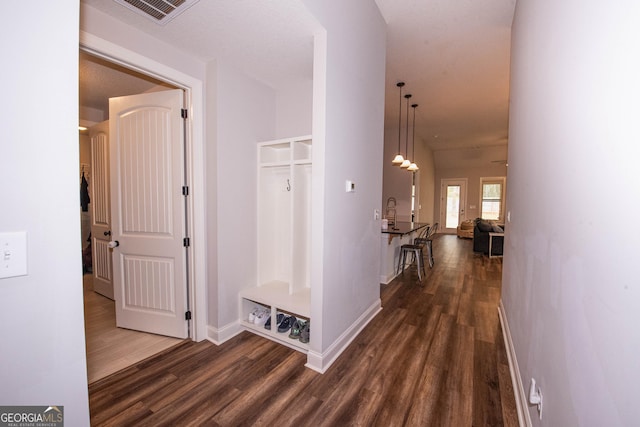corridor with dark wood-style floors, visible vents, and baseboards
