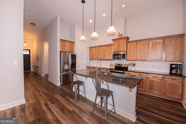 kitchen featuring a sink, brown cabinetry, a kitchen bar, and stainless steel appliances