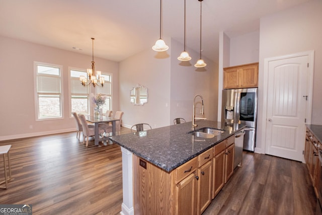kitchen featuring a sink, appliances with stainless steel finishes, dark stone countertops, and dark wood-style flooring
