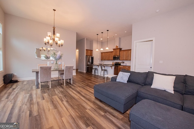 living room with baseboards, wood finished floors, a high ceiling, and a chandelier