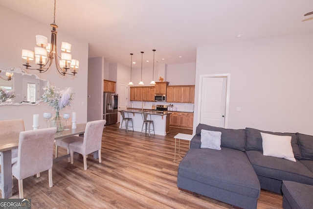 living room featuring wood finished floors, a high ceiling, and a chandelier