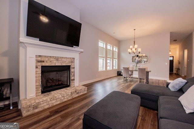 living area with baseboards, a notable chandelier, wood finished floors, and a fireplace