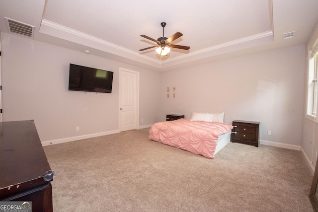 carpeted bedroom featuring a tray ceiling, visible vents, baseboards, and crown molding