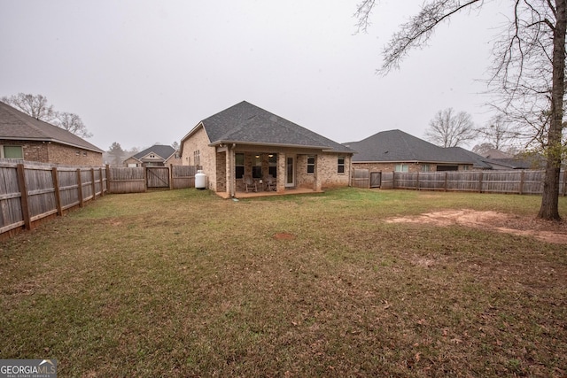 rear view of property featuring a gate, a lawn, a fenced backyard, and a patio area