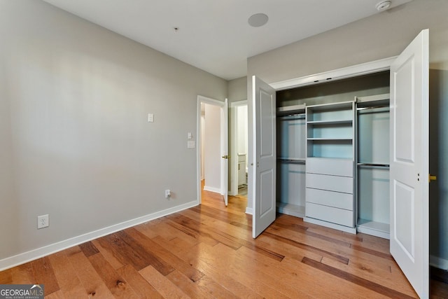 unfurnished bedroom with a closet, light wood-type flooring, and baseboards